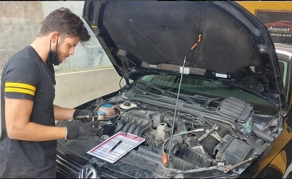 Mecânico da AssessorIA Car conferindo o motor de um carro com a lista de verificação