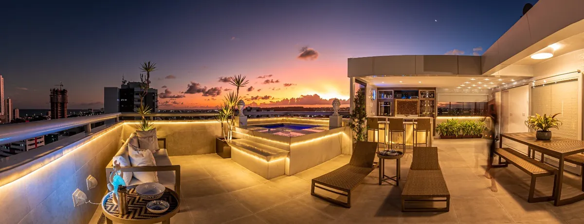 Cobertura com piscina, bar e área de descanso ao entardecer
