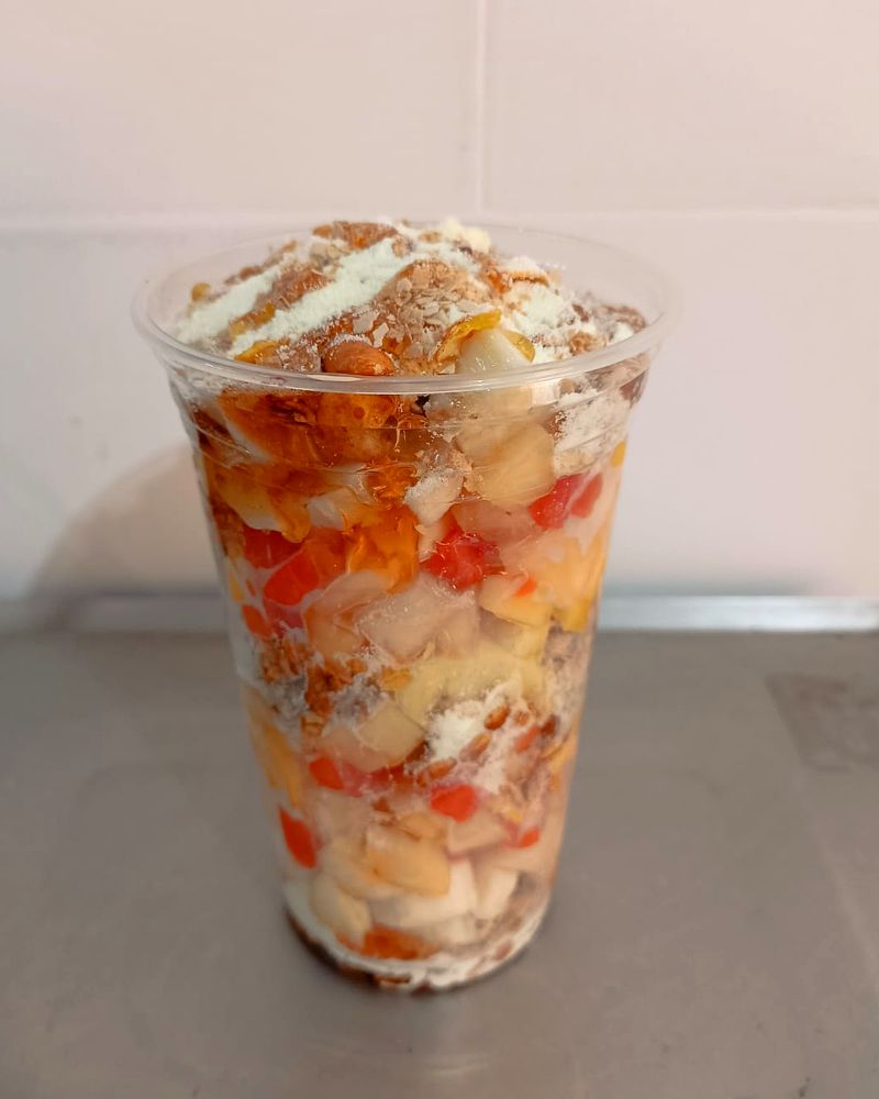 Copo de frutas picadas com creme e granola por cima