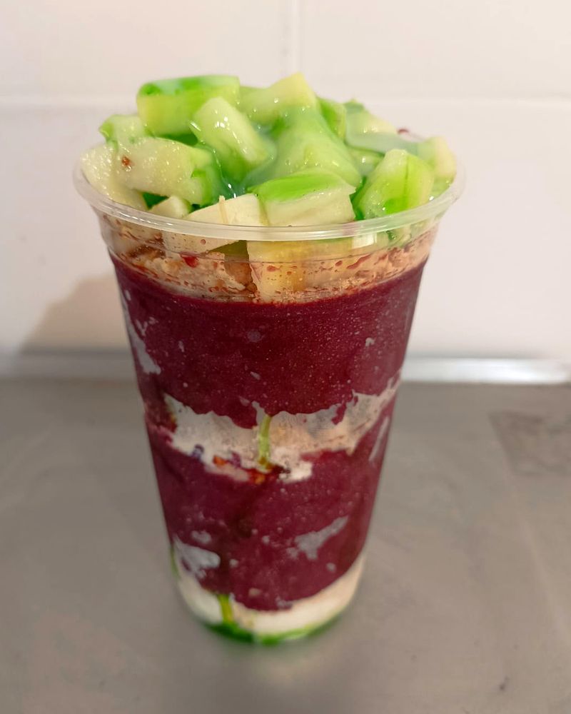 Copo de açaí em camadas com creme e frutas verdes por cima